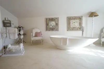 a bathroom with a large white tub and a chair at Mas aux gourmandises in Oppède
