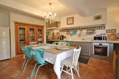 a kitchen with a table and chairs in a kitchen at Mas Bosca Brun in Cheval-Blanc