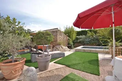a garden with a red umbrella and green grass at Mas Bosca Brun in Cheval-Blanc