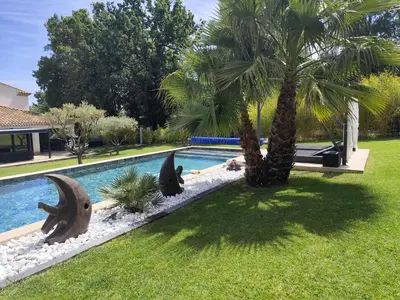a swimming pool with a palm tree next to a house at Chamarte villa piscine chauffées jardin clôturé Aix en Provence in Aix-en-Provence