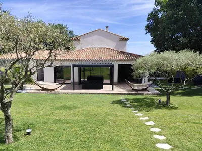 a garden with a house with a patio and trees at Chamarte villa piscine chauffées jardin clôturé Aix en Provence in Aix-en-Provence