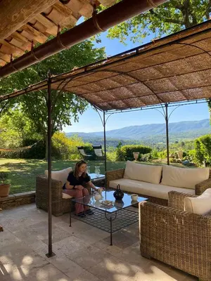 a woman sitting on a patio under a pergola at Provencal Villa With Panoramic Views In Luberon in Apt