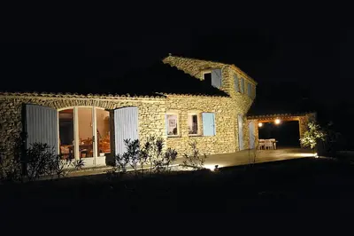 a stone house with a patio at night at Mas provençal - Beautiful Provencal farmhouse, heated pool in Murs