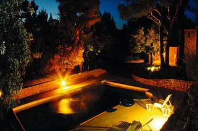 a swimming pool with lights in a backyard at night at Mas provençal - Beautiful Provencal farmhouse, heated pool in Murs
