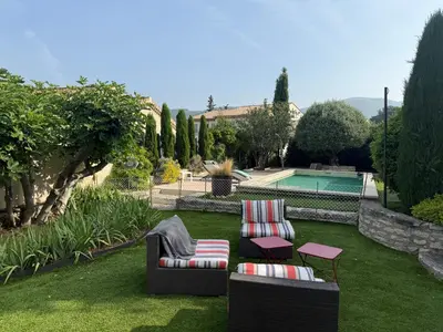 a garden with two chairs and a table and a pool at Cabanon Lourmarin in Lourmarin