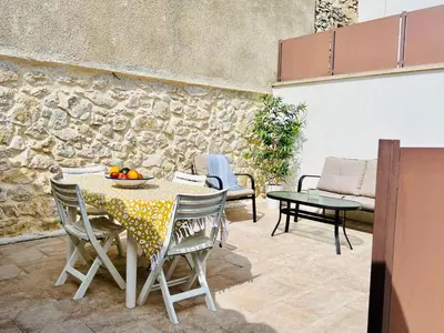 a patio with a table and chairs and a stone wall at L'Ecrin de Mérindol in Mérindol