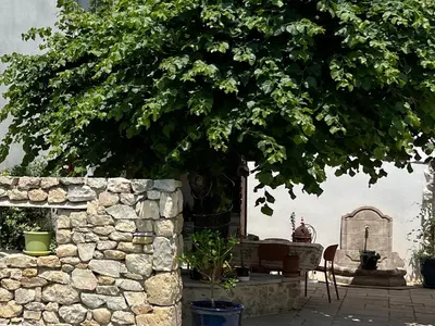 a stone wall with a table and a tree at L'Ecrin de Mérindol in Mérindol