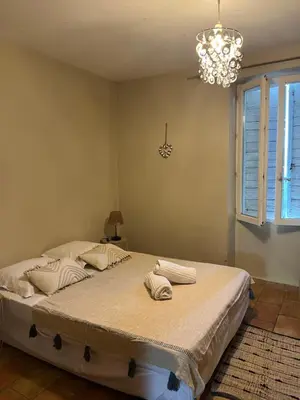 a bedroom with a large bed with a chandelier at Maison de vacances en pleine nature in Aurons