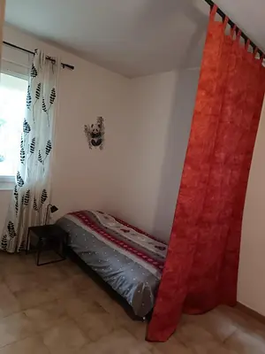 a bed in a room with a red curtain at L'Escale Pernoise, 2-6 personnes in Pernes-les-Fontaines