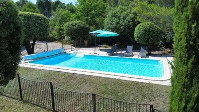 a swimming pool in a yard with an umbrella at Bastide Clementine in LʼIsle-sur-la-Sorgue