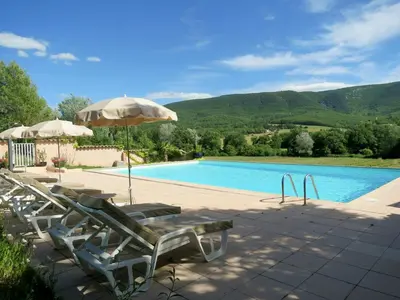 a swimming pool with chairs and an umbrella and a pool at Provençal Villa With Luberon Views in Céreste