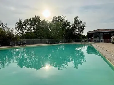 a large blue swimming pool with the sun in the background at Douceur de vivre en Provence in Saint-Saturnin-lès-Avignon