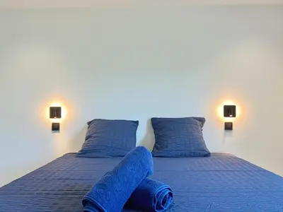 a bed with blue sheets and pillows in a room at Casa Corniou - Calme, Village Provençal, 3 chambres, 2 SDB, 8 personnes in Cornillon-Confoux