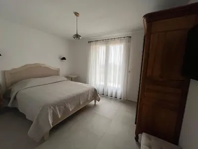 a white bedroom with a bed and a window at Maison dans un hameau avec piscine in Gordes