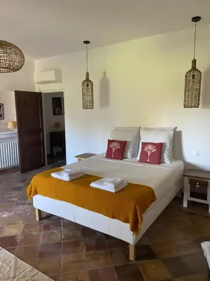 a bedroom with a large white bed with red pillows at The Farmhouse in the shade of the plane trees in Cavaillon