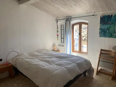 a bedroom with a large bed with a window at Charming village house in Alleins