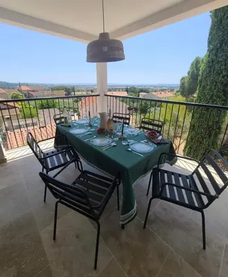 a table with chairs and a green tablecloth on a balcony at le petit 105 villa neuve avec piscine in La Fare-les-Oliviers