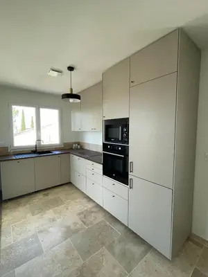 a kitchen with white cabinets and a black appliance at le petit 105 villa neuve avec piscine in La Fare-les-Oliviers