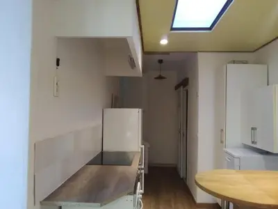 a kitchen with white appliances and a wooden table at Tranquility of Lub in this duplex in La Bastide-des-Jourdans