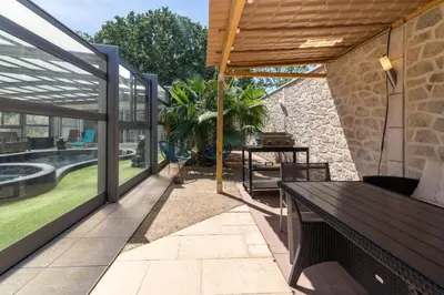 a patio with a wooden table and a pool at Le logis de la castagne in Caumont-sur-Durance
