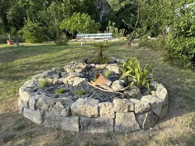 a rock fire pit in a yard with a bench at Studio terrasse in Aix-en-Provence
