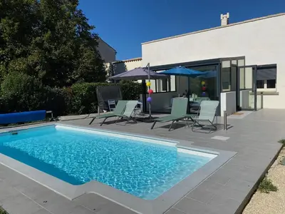 a swimming pool with chairs and an umbrella next to a house at Chez Simone, maison calme et indépendante, piscine in Cavaillon