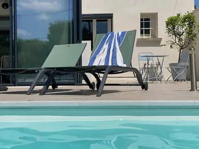 a lounge chair next to a swimming pool at Chez Simone, maison calme et indépendante, piscine in Cavaillon
