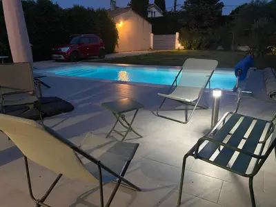 a group of chairs sitting next to a pool at night at Chez Simone, maison calme et indépendante, piscine in Cavaillon