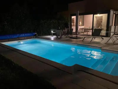 a swimming pool at night with a table and chairs at Chez Simone, maison calme et indépendante, piscine in Cavaillon