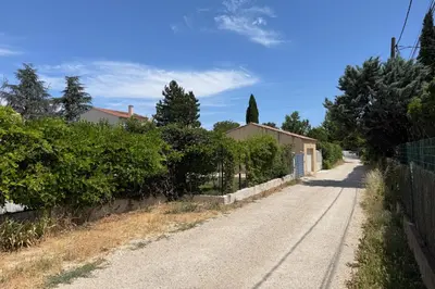 an empty road with a fence and trees on the side at Chez Simone, maison calme et indépendante, piscine in Cavaillon