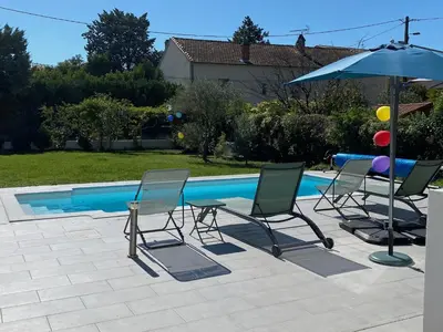 a group of chairs and an umbrella next to a pool at Chez Simone, maison calme et indépendante, piscine in Cavaillon