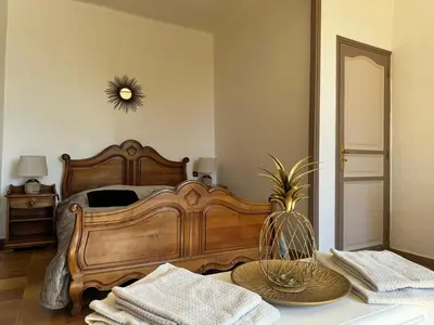 a bedroom with a wooden bed and a table with towels at Domaine Régine in Le Puy-Sainte-Réparade