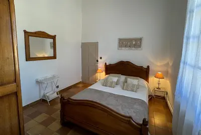 a bedroom with a wooden bed and a mirror at Domaine Régine in Le Puy-Sainte-Réparade
