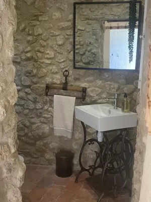 a bathroom with a sink and a stone wall at Domaine Régine in Le Puy-Sainte-Réparade