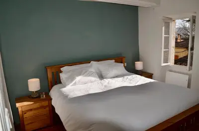 a bedroom with a white bed with two night stands and a window at La Serre in Viens