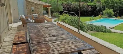 a wooden deck with a table next to a swimming pool at le mas du luberon rouge in Cheval-Blanc