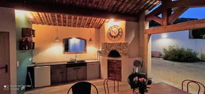 a kitchen with a fireplace and a clock on the wall at le mas du luberon rouge in Cheval-Blanc