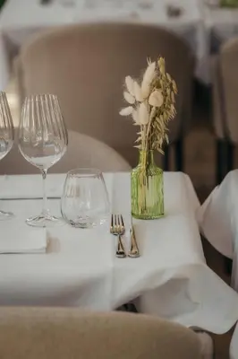 a table with glasses and a vase with flowers on it at La Bastide de Paula in Aix-en-Provence
