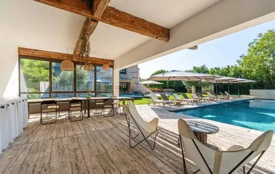an outdoor deck with chairs and tables and a swimming pool at Coeur des Hommes in Le Thor