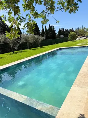 a swimming pool with blue water in a yard at Charmants duplex , Clim et Piscine in Aix-en-Provence