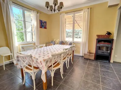 a dining room with a table and chairs and a stove at La Villa Luberonnaise in Robion en Luberon