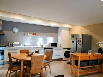 a kitchen with a table and a kitchen with a refrigerator at Spacieux 74 m2 Standing Clim & Parking Privé Centre Ville in LʼIsle-sur-la-Sorgue