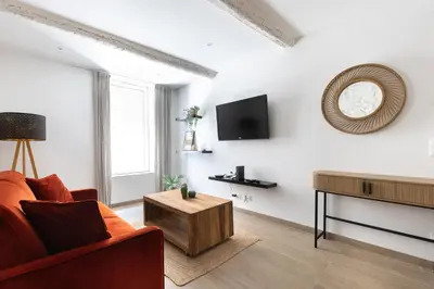 a living room with a red couch and a table at Le Cocon du Luberon - Clim - Wifi - Hypercentre in Apt