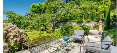 a patio with a glass table and chairs and trees at Villa de charme avec Piscine & Vue panoramique en plein Centre-ville d'Aix-en-Provence in Aix-en-Provence