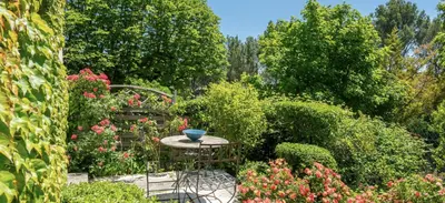 a garden with a table and chairs and flowers at Villa de charme avec Piscine & Vue panoramique en plein Centre-ville d'Aix-en-Provence in Aix-en-Provence