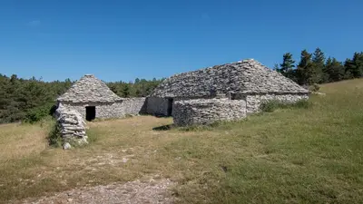 an old stone building on a hill with trees at Appartement dans maison de caractère avec piscine in Banon