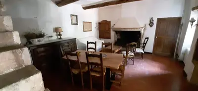 a dining room with a table and chairs and a fireplace at Maison de famille traditionnelle provençale in Gordes