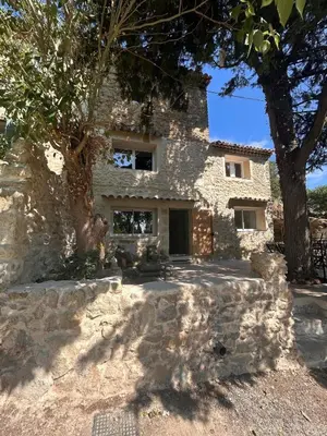 a stone house with a tree in front of it at La Maison Du Jas in Puyvert