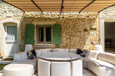 a patio with white furniture and a stone wall at Gîte Terrasse in Gordes