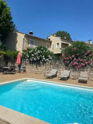 a swimming pool with chairs and a house in the background at La Rochère - Hamlet with swimming pool in Gordes in Gordes